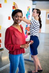Woman smiling while colleague writing on white board