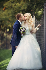 elegant stylish groom with his happy gorgeous blonde bride on th