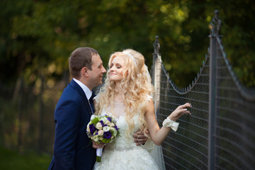 elegant stylish groom with his happy gorgeous blonde bride on th