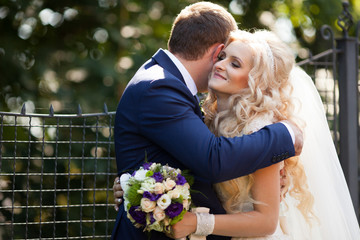 elegant stylish groom with his happy gorgeous blonde bride on th