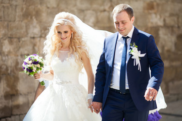 elegant stylish groom with his happy gorgeous blonde bride on th