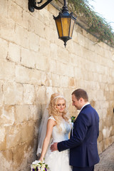 elegant stylish groom with his happy gorgeous blonde bride on th