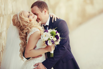 elegant stylish groom with his happy gorgeous blonde bride on th