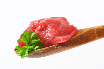 Raw beef meat on wooden spoon