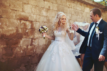 elegant stylish groom with his happy gorgeous blonde bride on th