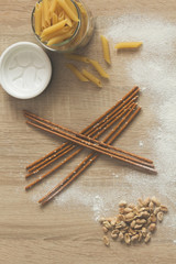 Macaroni on the bowl and peanuts on wooden background.