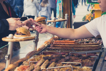 person buying grilled suasage at a fair - obrazy, fototapety, plakaty