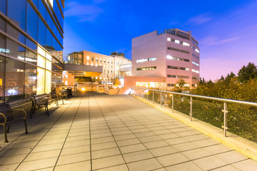 empty footpath and modern building with illuminated blue sky