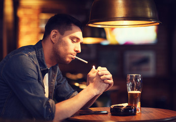 man drinking beer and smoking cigarette at bar