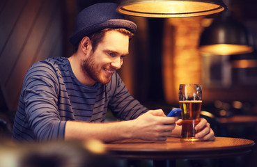 man with smartphone and beer texting at bar