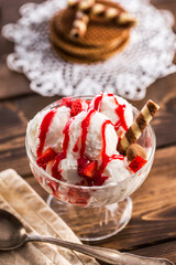 Glass ramekin with ice cream and spoon on table