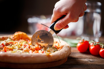Slicing fresh pizza with roller knife. 