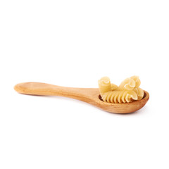 Wooden spoon filled with dry rotini pasta over isolated white background