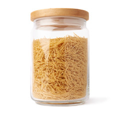 Glass jar filled with dry noodles pasta over isolated white background