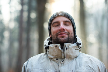 Man in nature wearing warm clothing looking happy and peaceful