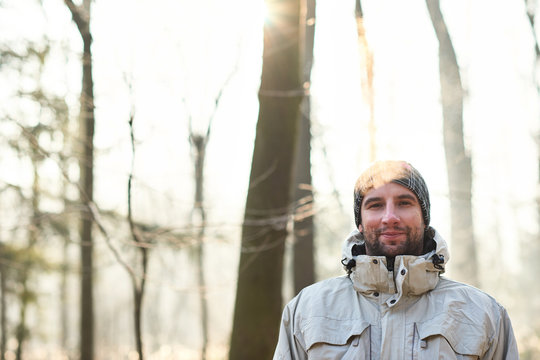 Man smiling in a winter forest with gentle sunlight