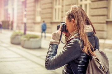 Pretty young female tourist photographer taking pictures in the city