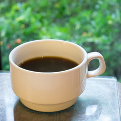 The close up of cup of black coffee in the ceramic coffee cup on wooden table at restaurant.