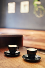 Two cappucinos on a wooden counter in coffee shop