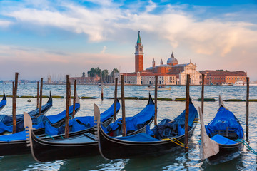 Gondolas moored by Saint Mark square with San Giorgio di Maggiore church in the background in the evening, Venice, Italia