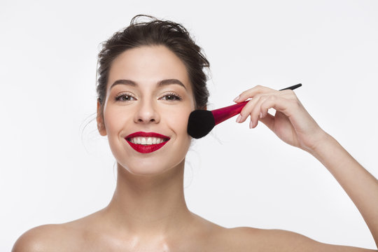 Image of a smiling beautiful girl with red lipstick over white background. hanging the brush