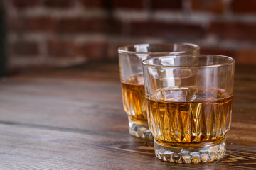 Glasses of whiskey with ice on wood.