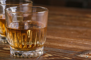 Glasses of whiskey with ice on wood.