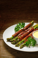 grilled green asparagus wrapped in prosciutto bacon on rustick wood, vertical, copy space