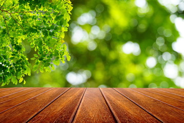 perspective wood table empty space and nature green leaves on abstract blur bokeh background. 