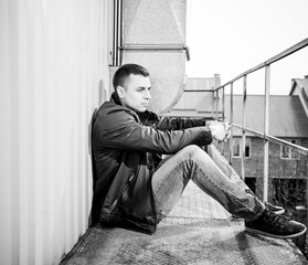 man sitting at old metallic balcony