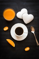 Obraz na płótnie Canvas Black coffee, orange juice, cakes in the shape of a heart and kumquat on a black background