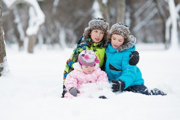 Fototapeta na wymiar Portrait of Two cheerful happy boys and baby girl in winter park