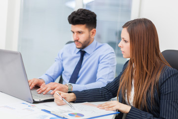     Smiling business people using a laptop computer in their office