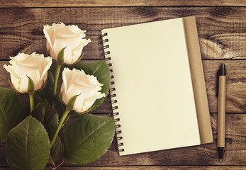 White rose flowers with notebook and pen