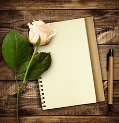 White rose flower with notebook and pen