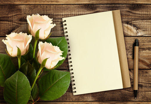 White rose flowers with notebook and pen