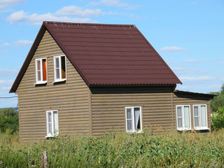 Fototapeta na wymiar Modern two-storeyed summer cottage against a blue sky