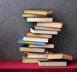 Stack of books on the table with a red tablecloth.
