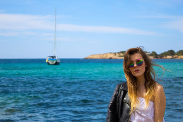 Pretty girl at the turquoise seaside with boat and sea coast