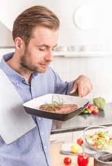 Man or chef smelling grilled steak with rosemary from the pan