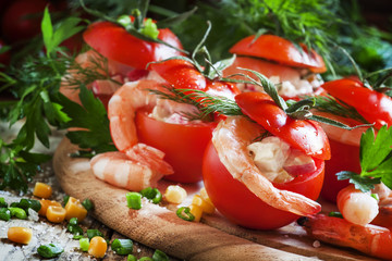 Tomatoes stuffed with shrimp meat and corn on a wooden plate, se