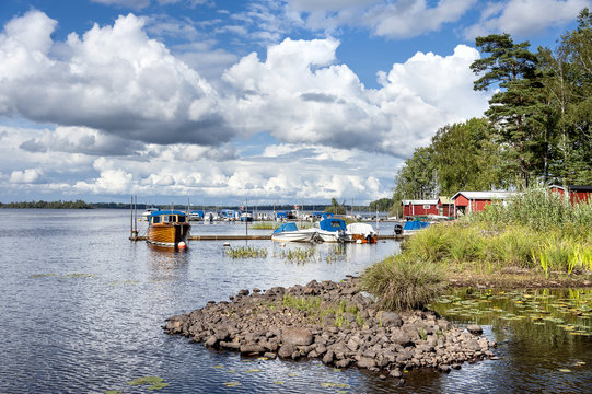 Sweden - Coastal scene with old red traditional wooden houses near the water, landing bridge and motor boats