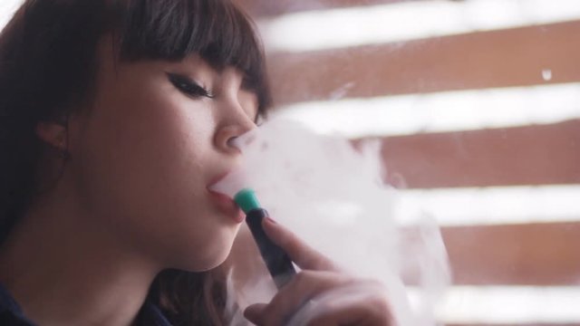 Beautiful young woman inhaling hookah. girl smoking shisha in cafe. Close-up