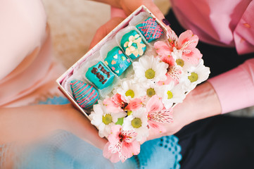 Hands holding gift box filled with flowers and fruit candy