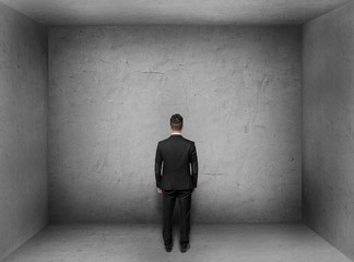 Obraz premium Back view of businessman inside empty concrete room