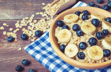 Oatmeal with blueberries and banana in wooden bowl