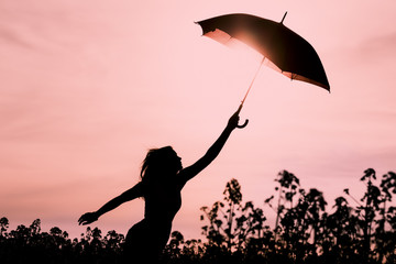 Abgekoppelte Frau in Silhouette mit Schirm fliegt in die Zukunft. Warme Szene mit fliegendem Mädchen. Zeigt die Vorstellungskraft und den Aufbruch zu neuen Horizonten wie Klimawechsel oder Achtsamkeit