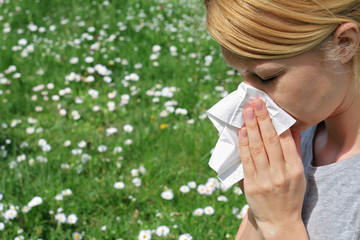 Pollen allergy, Springtime. Woman sneezing in a tissue