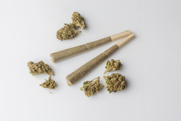 Two medical cannabis rolled joints with dried marijuana buds around on white background from above - obrazy, fototapety, plakaty