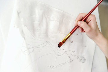 Woman fashion designer creates a dress sketch.